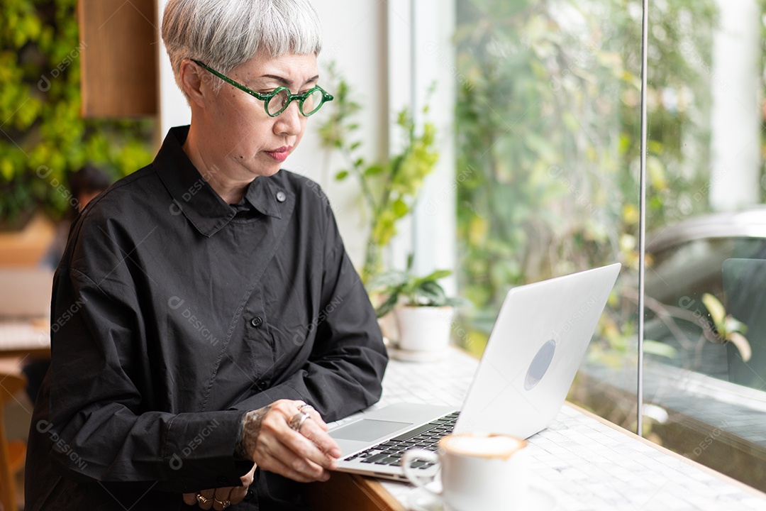 Mulher sênior asiática ativa assistindo e trabalhando no laptop no