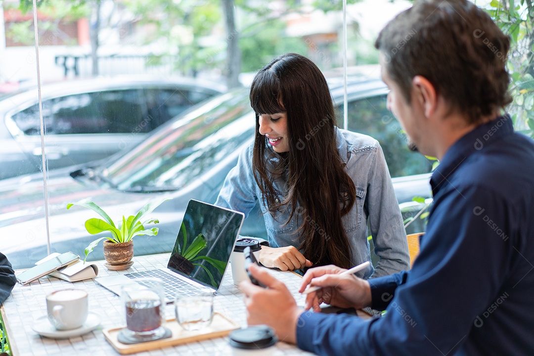 Homem e mulher se encontram e trabalham no laptop no café