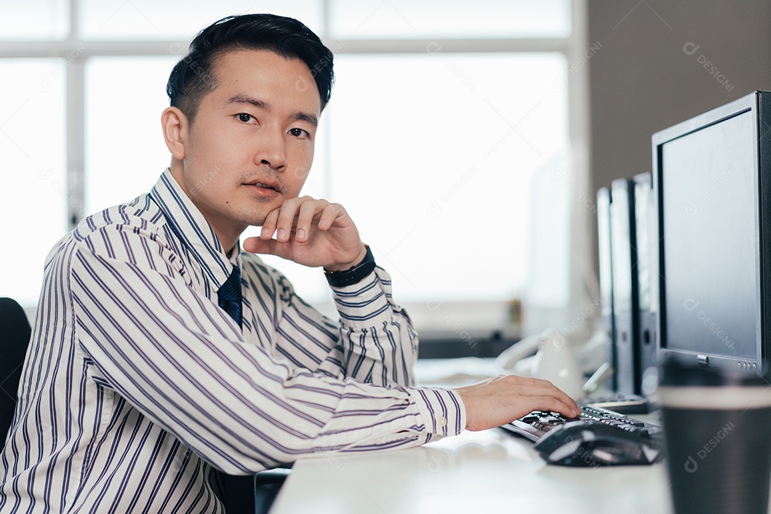 Funcionário do sexo masculino trabalhando no computador na mesa do escritório.