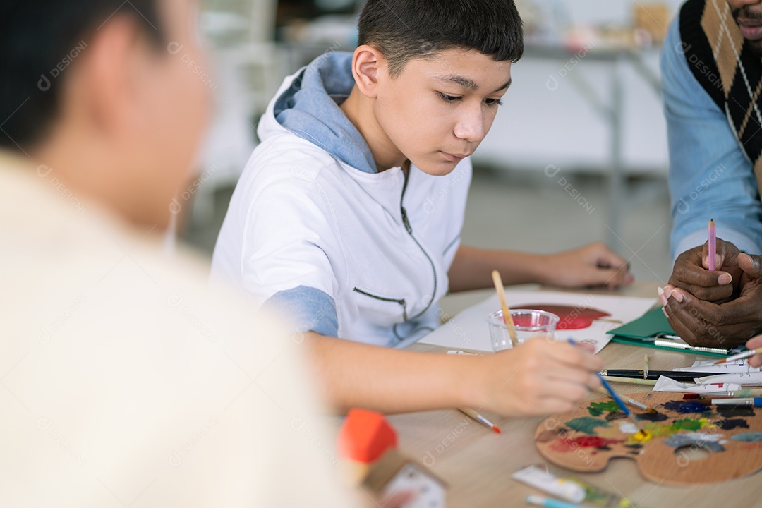 Menino gosta de desenhar e pintar na aula de artes