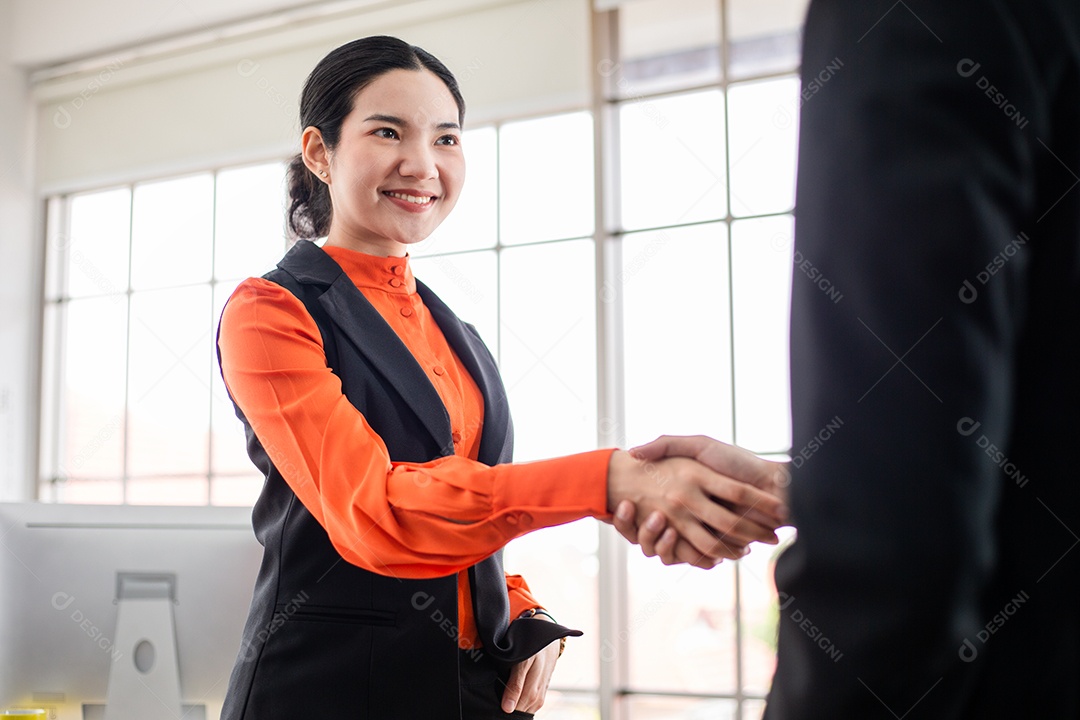 Mulher asiática sorridente apertando a mão com a parceria do colega