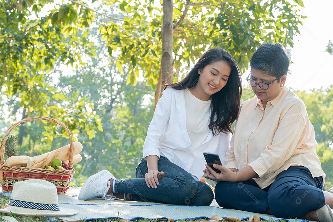 Filha asiática ensinando mãe usando e jogando no celular