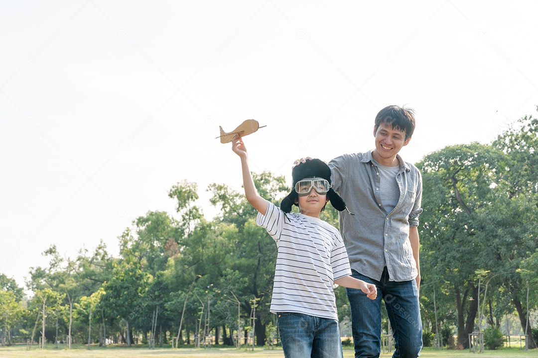 Feliz pai asiático jogando avião de papel com filho no parque