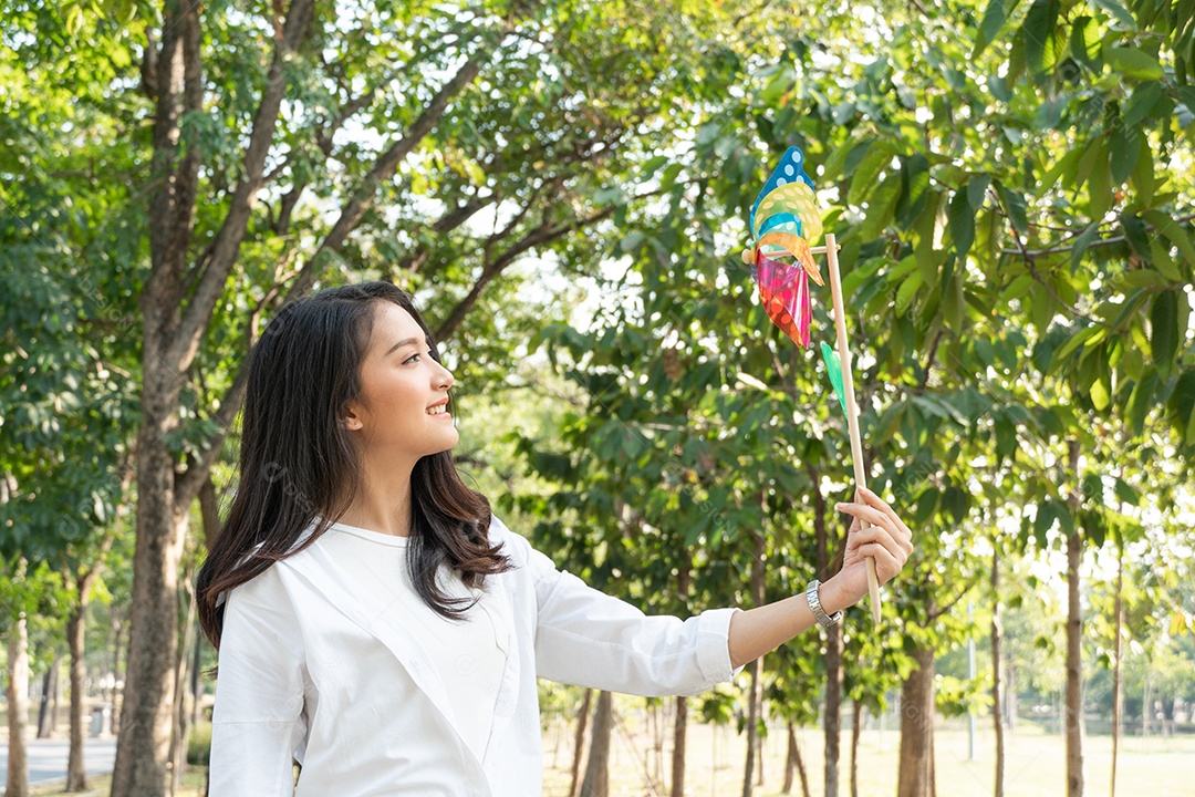 Mulher saudável asiática feliz jogando uma turbina no parque