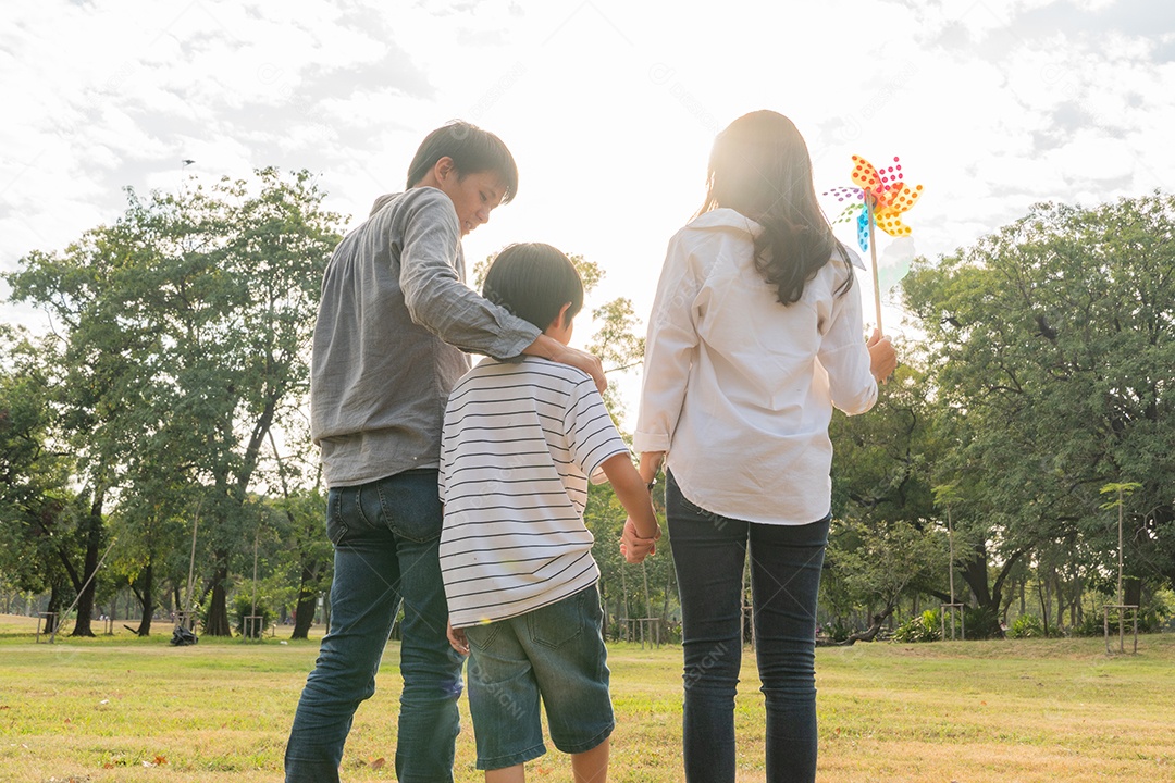 Vista traseira da família asiática feliz caminhando no parque