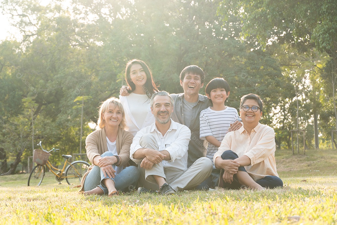 Grupo de retratos de pessoas de diversidade sentadas na grama e tirando fotos juntas.