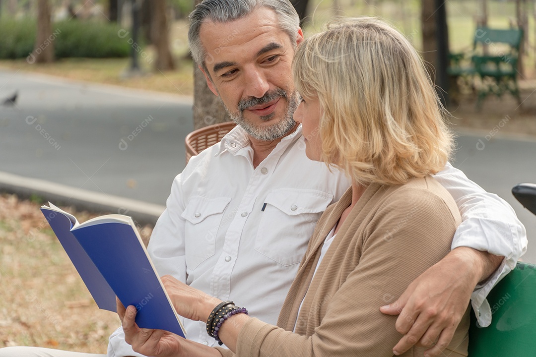 Caucasiano casal sênior lendo livro juntos no banco