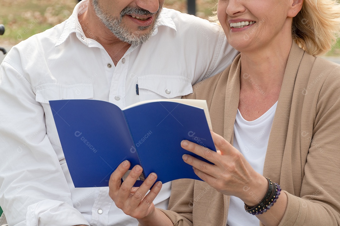 Casal sênior sorrindo e rindo enquanto lê um livro juntos