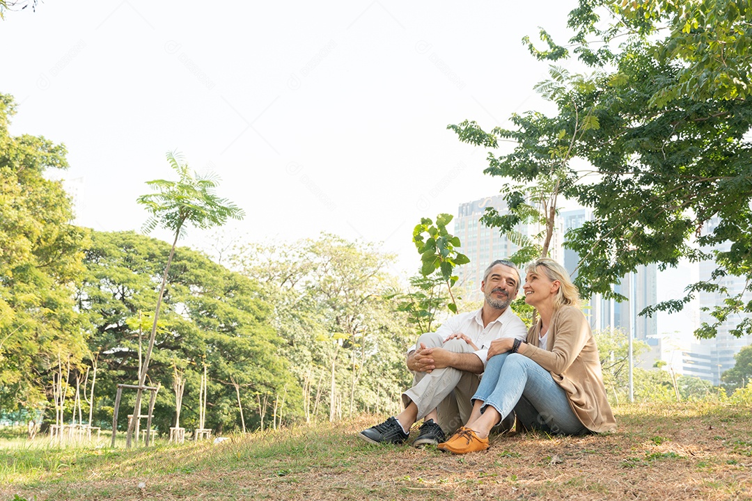 Casal caucasiano sênior sentado na grama relaxando no parque juntos