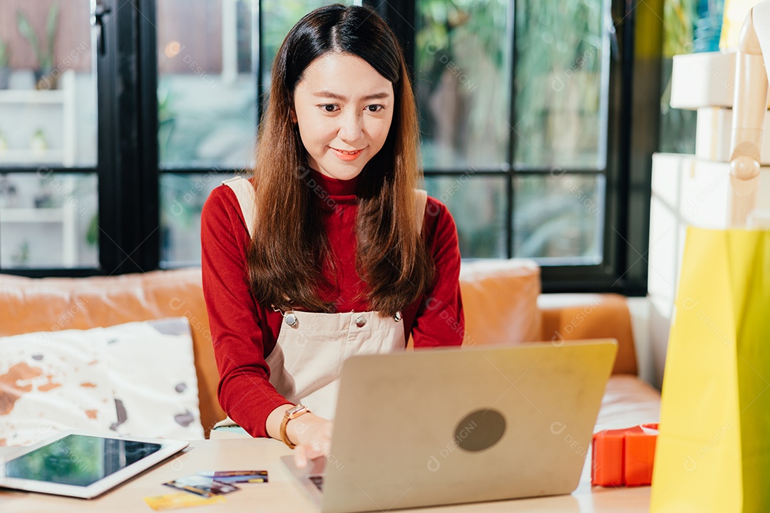 Proprietário de loja de pequenas empresas usando laptop verificando o pedido do cliente