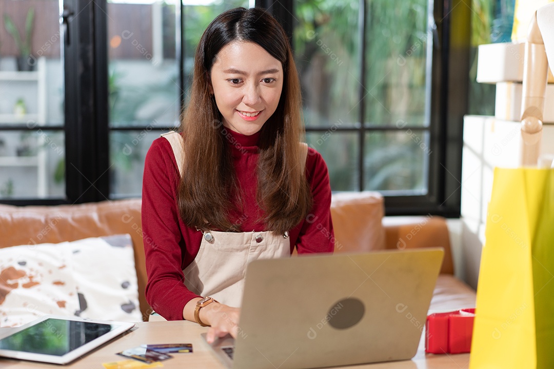 Proprietário de loja de pequenas empresas verificando o pedido do cliente no laptop