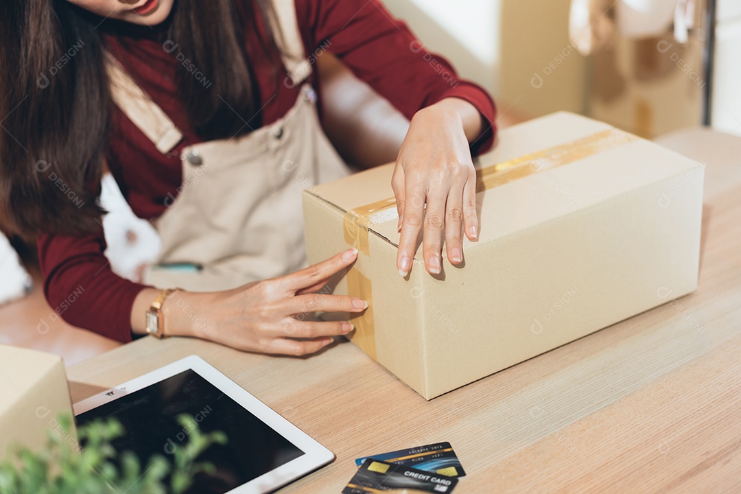 Mão do dono da loja embalando a caixa de encomendas se preparando para a entrega