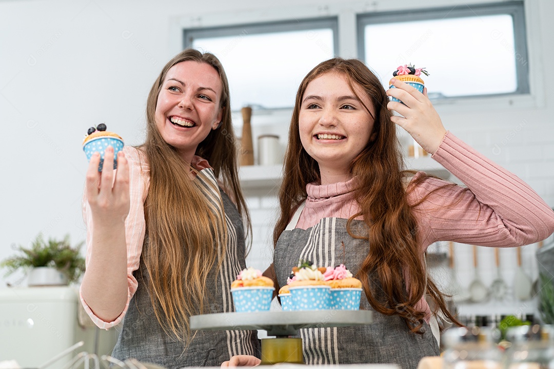 Mãe feliz e filha orgulhosa mostrando bolo caseiro