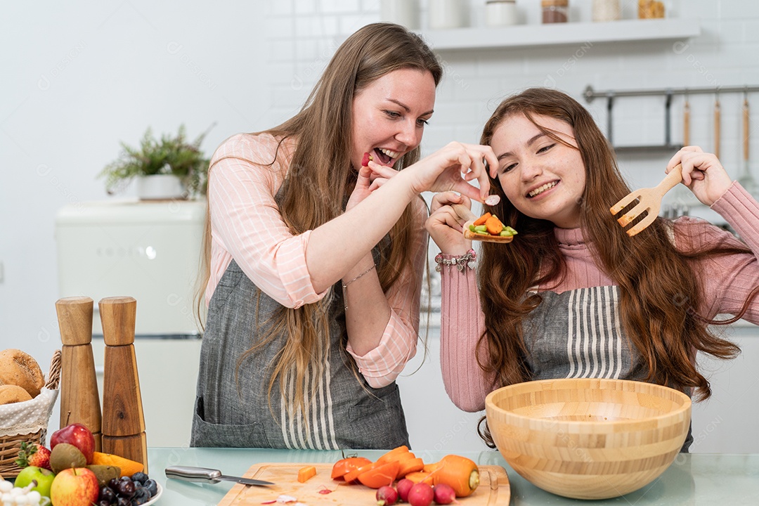 Feliz mãe e filha gostam de cozinhar salada caseira