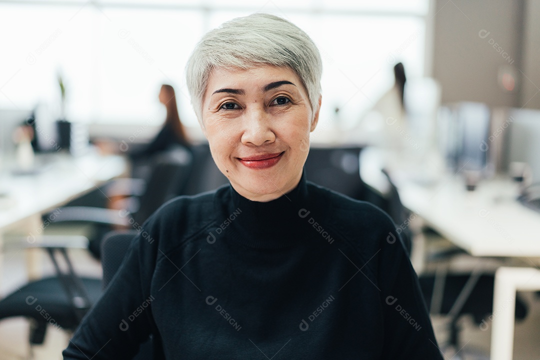 Retrato da gerente sênior asiática na mesa do escritório