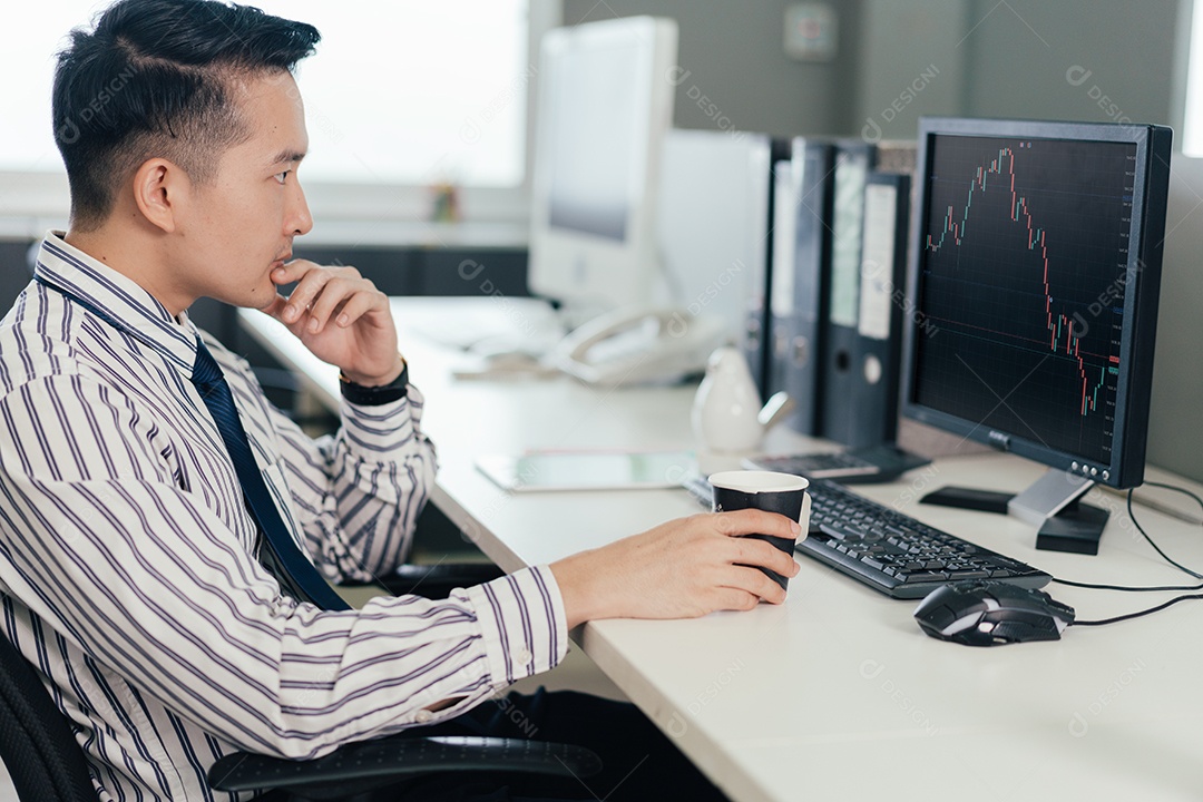 Comerciante masculino asiático observando e analisando o gráfico no monitor