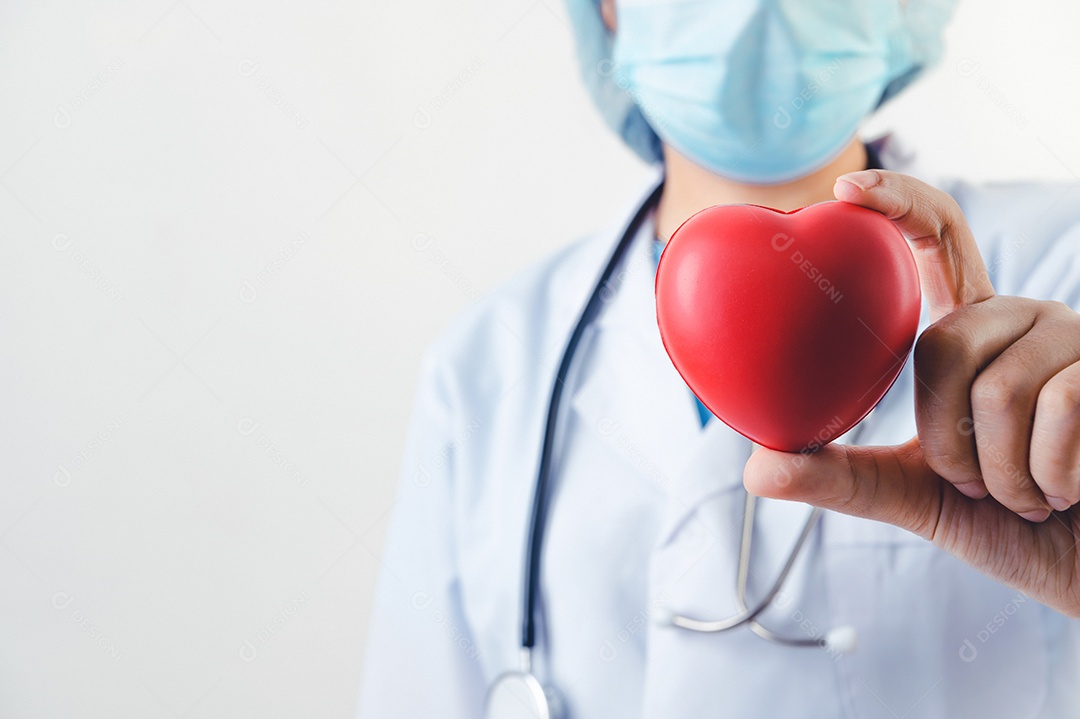 Close up do coração vermelho na mão do doutor com estetoscópio no fundo branco. Pessoas médicas e conceito de praticante de cardio. Doação de coração e tema de cuidados de saúde de resgate de vida.