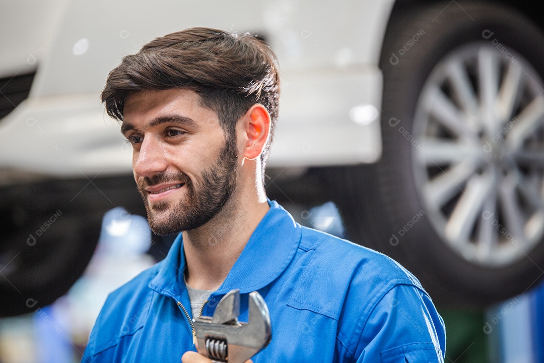 Mecânico sorridente segurando a chave na oficina mecânica