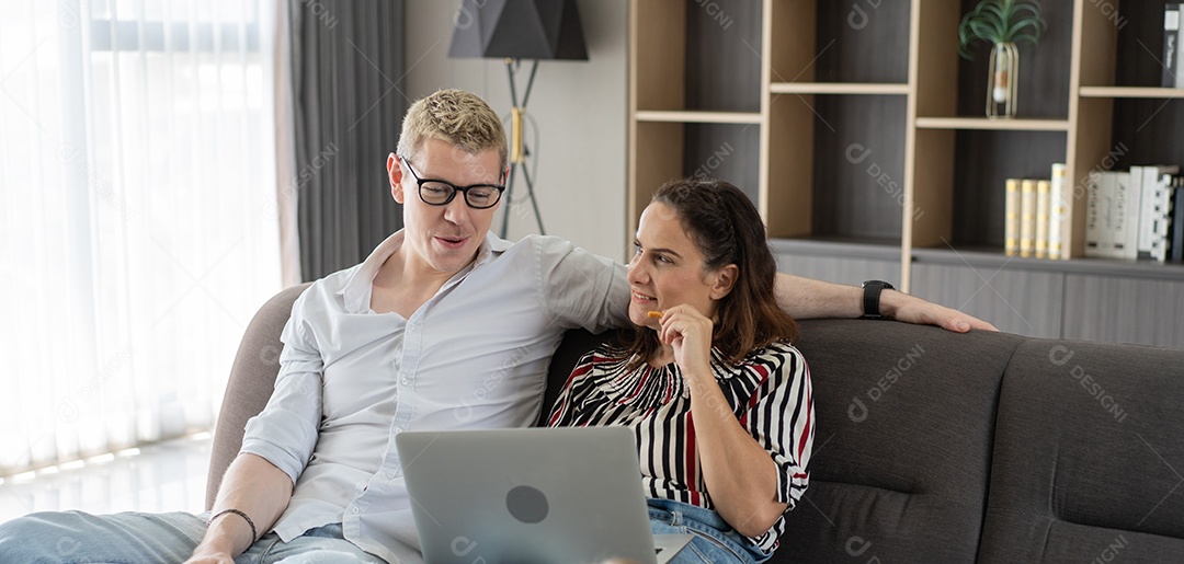 Casal caucasiano conversando e olhando no laptop juntos
