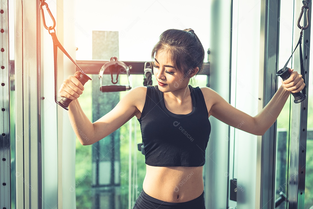 Mulher jovem asiática fazendo exercícios de corda elástica no ginásio cross fitness. Treinamento de força e conceito de beleza e saúde muscular. Equipamentos esportivos e tema do Sport club center.