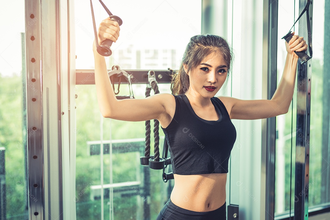 Mulher jovem asiática fazendo exercícios de corda elástica no ginásio cross fitness. Treinamento de força e conceito de beleza e saúde muscular. Equipamentos esportivos e tema do Sport club center.