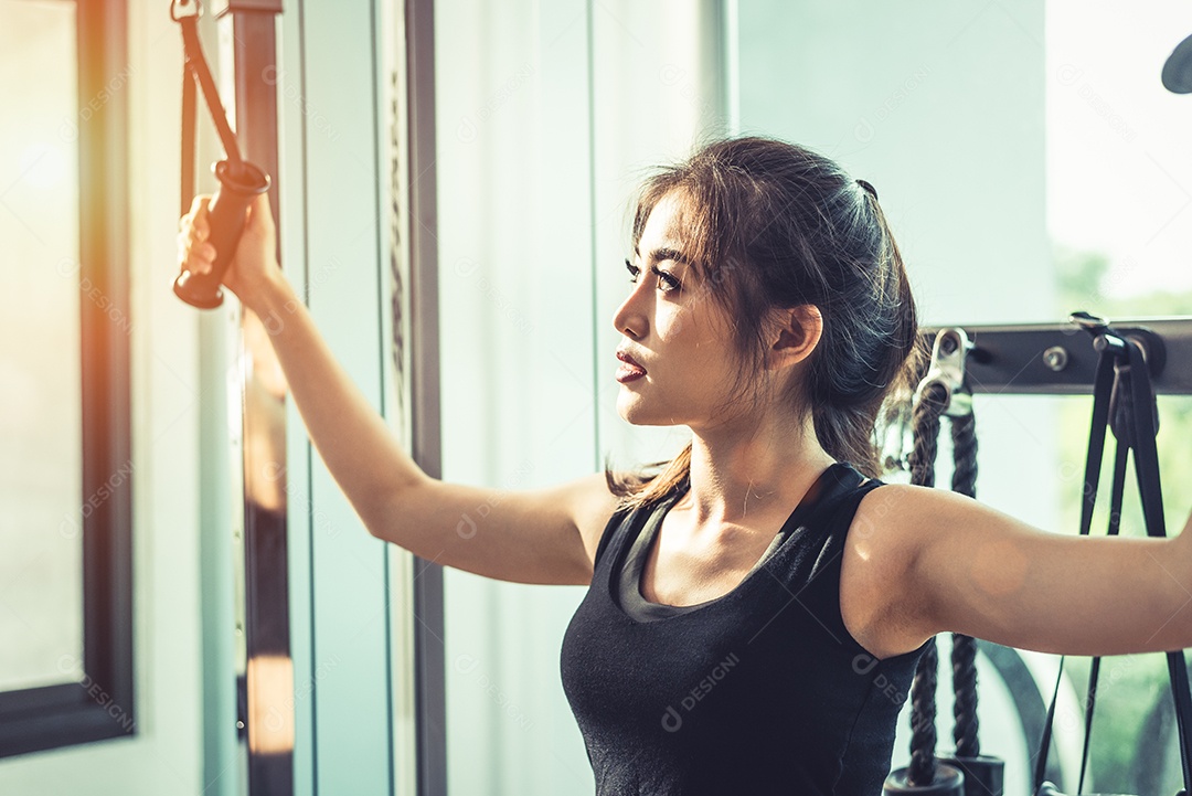 Mulher jovem asiática fazendo exercícios de corda elástica no ginásio cross fitness. Treinamento de força e conceito de beleza e saúde muscular. Equipamentos esportivos e tema do Sport club center.