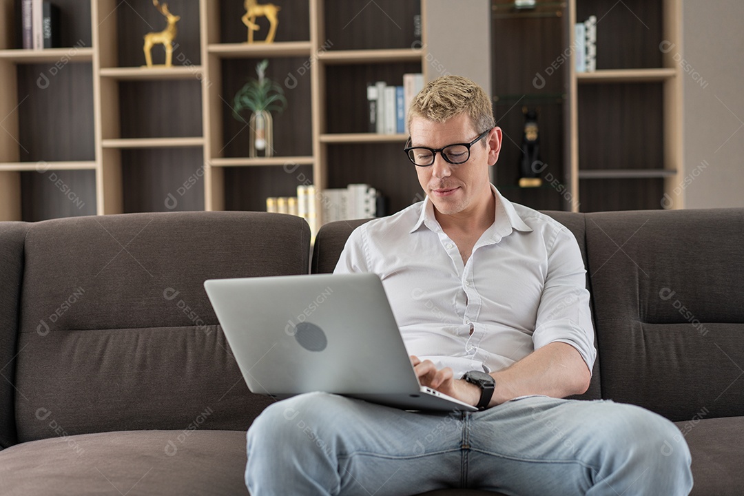 Homem trabalhando com laptop ou assistindo filme no sofá da sala