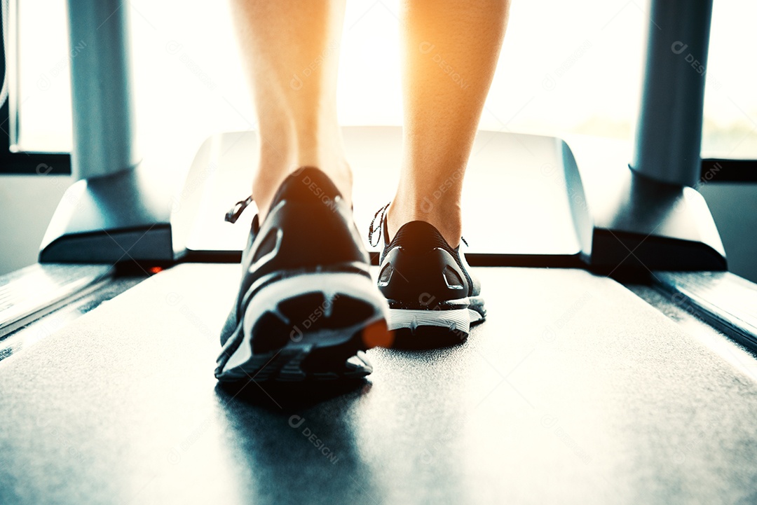 Close-up de pessoas que se exercitam na esteira. Close-up de pernas de mulher andando em esteira no clube desportivo. Conceito de construção de fitness e corpo. Conceito de treinamento de treino e força. Tema do clube desportivo.