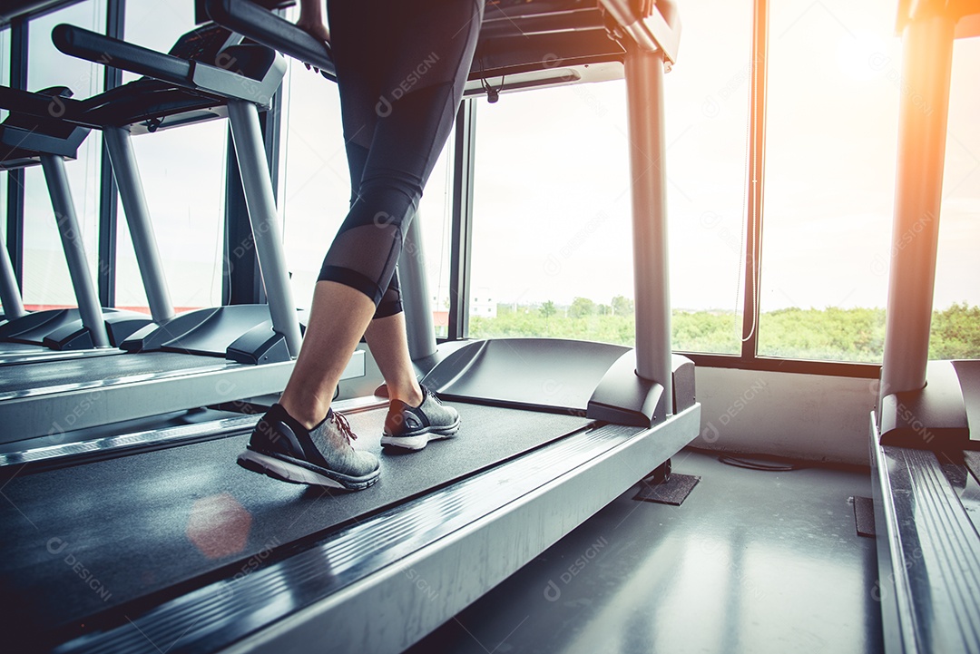 Close-up de pessoas que se exercitam na esteira. Close-up de pernas de mulher andando em esteira no clube desportivo. Conceito de construção de fitness e corpo. Conceito de treinamento de treino e força. Tema do clube desportivo.