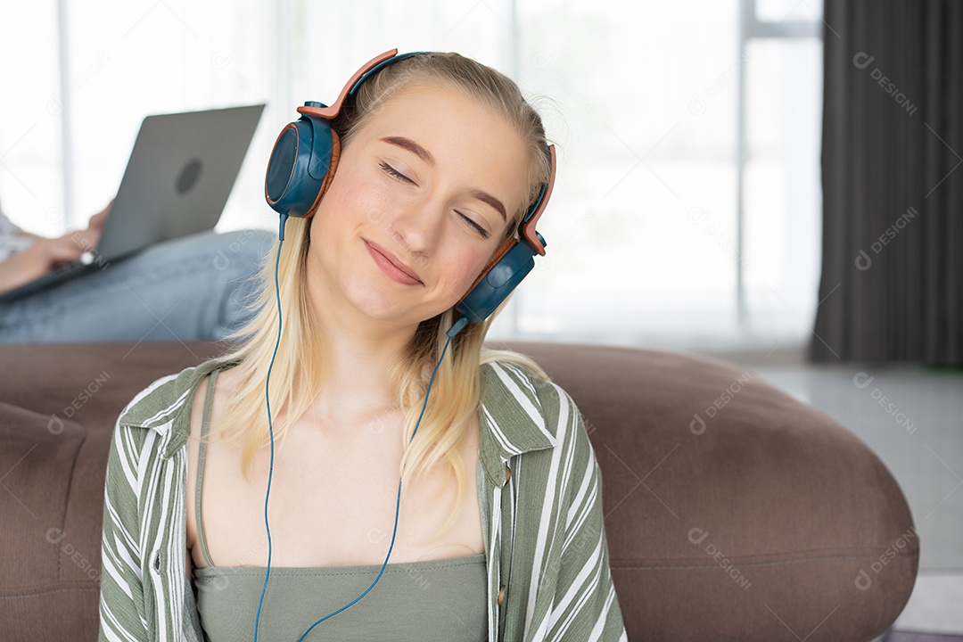 Menina caucasiana feliz ouve música com fone de ouvido relaxando