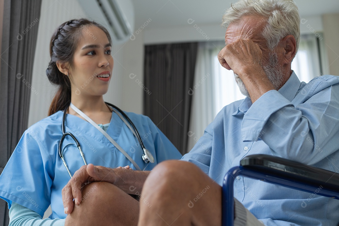 Cuidador de enfermeira consolando paciente do sexo masculino deprimido em cadeira de rodas.