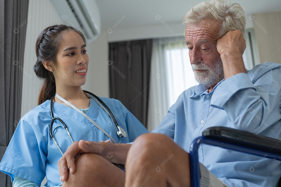 Cuidador de enfermeira consolando paciente do sexo masculino deprimido em cadeira de rodas.