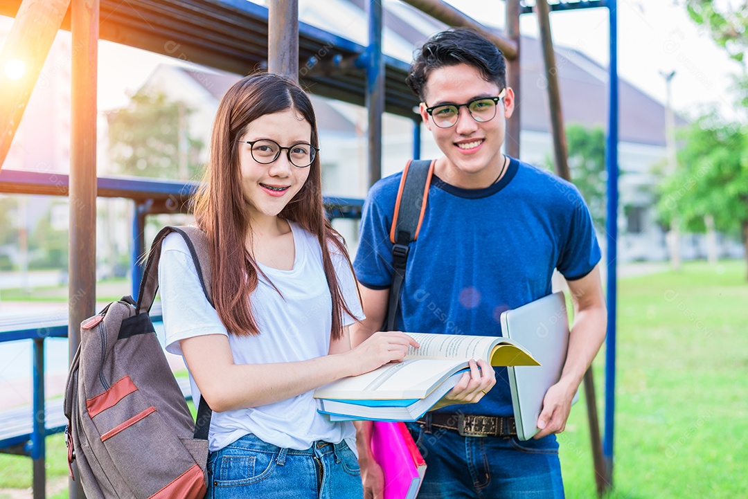 Dois jovens universitários asiáticos discutindo sobre a leitura de livros e o uso do laptop para pesquisar e aprender conhecimento. Conceito de educação e amizade. Felicidade e conceito de aprendizagem. Amantes e amigo tema.