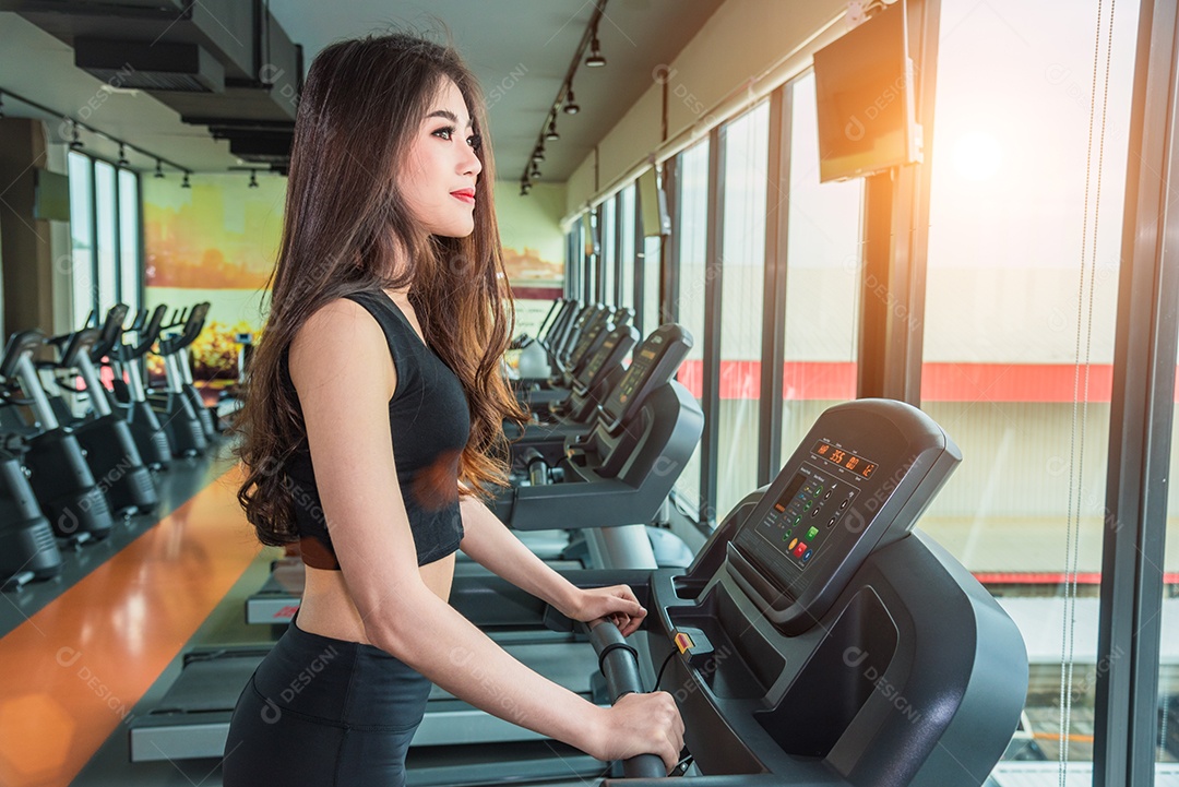 Mulher esportiva asiática andando ou correndo em equipamentos de esteira na academia de ginástica. Conceito de esporte e beleza. Tema de treino e treinamento de força. Tema Cardio e Dieta