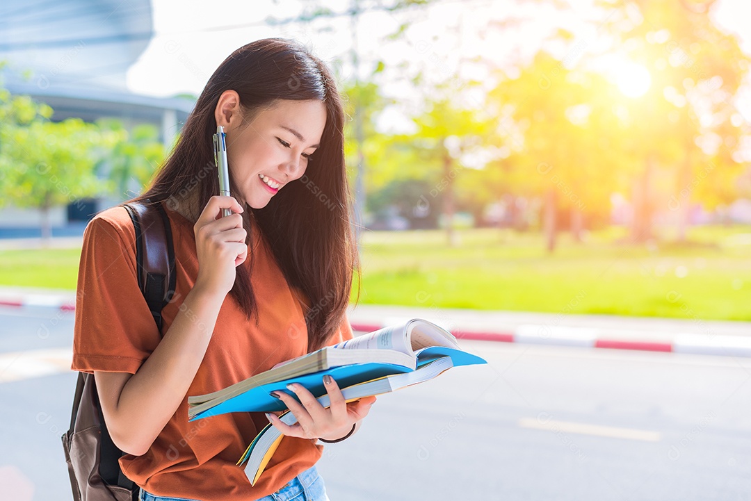 Jovem universitária asiática fazendo lição de casa e lendo livros para o exame final no campus. Conceito de universidade e estudante. Conceito de estilo de vida e beleza. Adolescente e tema de aprendizagem.