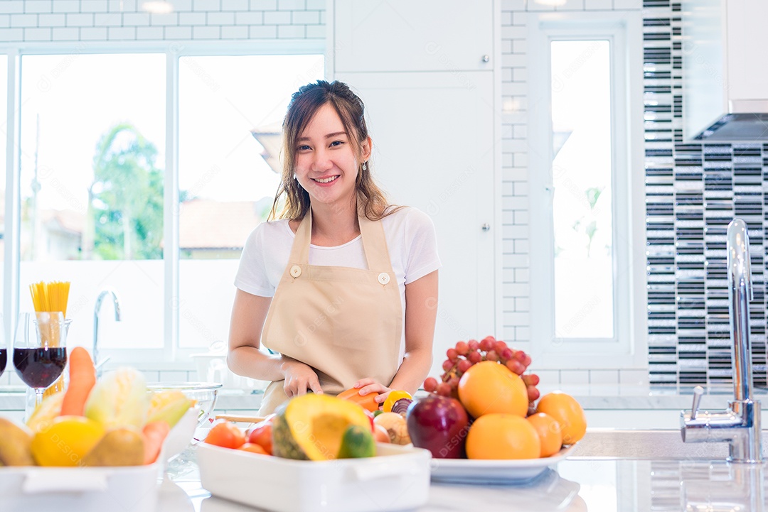 A jovem asiática prepara-se para preparar o jantar na cozinha. Conceito de alimentos e bebidas. Conceito de beleza e mãe solteira. Vida feliz e tema de estilo de vida. Interior e fundo da decoração.