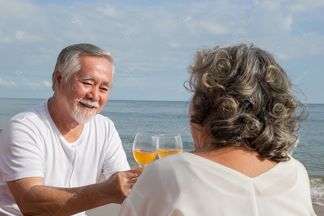 Casal sênior asiático brindando com copos e gosta de beber vinho