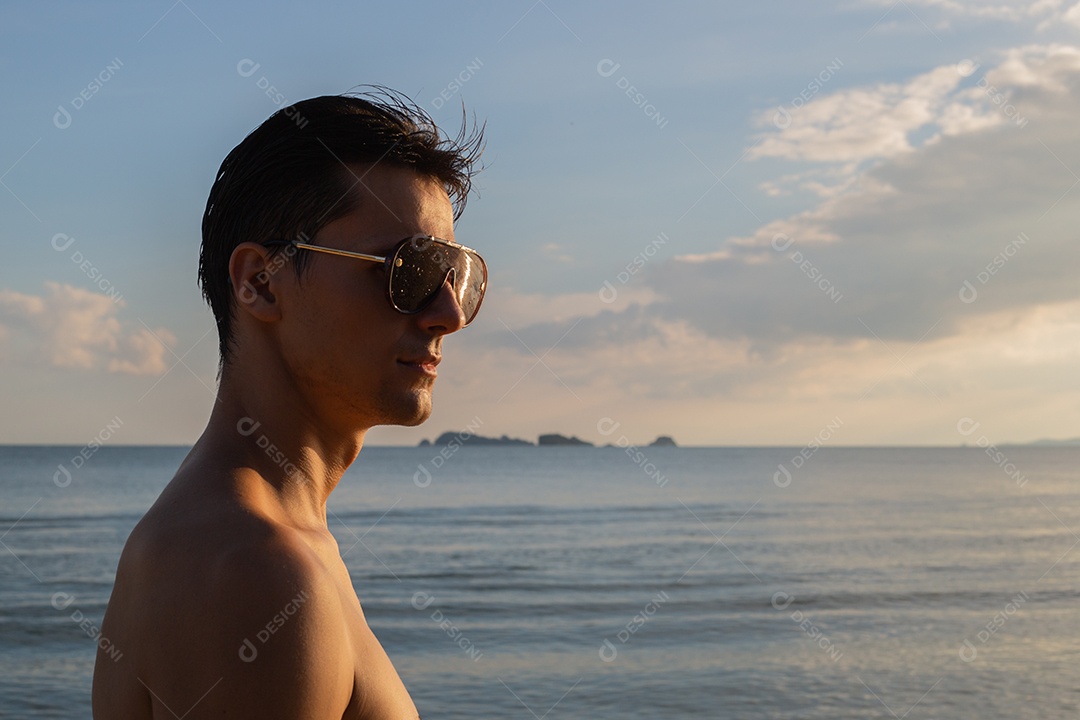 Retrato de homem caucasiano em topless usando óculos escuros na praia