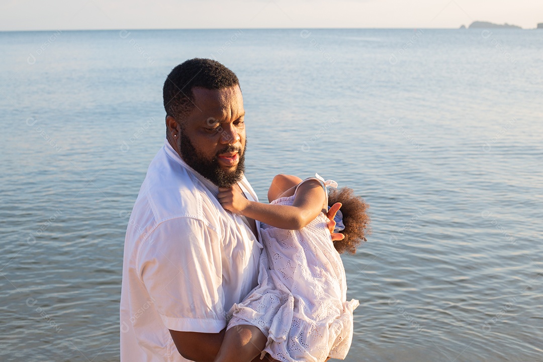 Afro-americano pai brincalhão carregando filha na praia