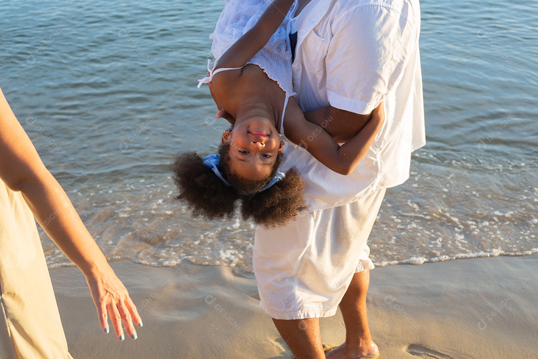 Afro-americano pai brincalhão carregando filha na praia