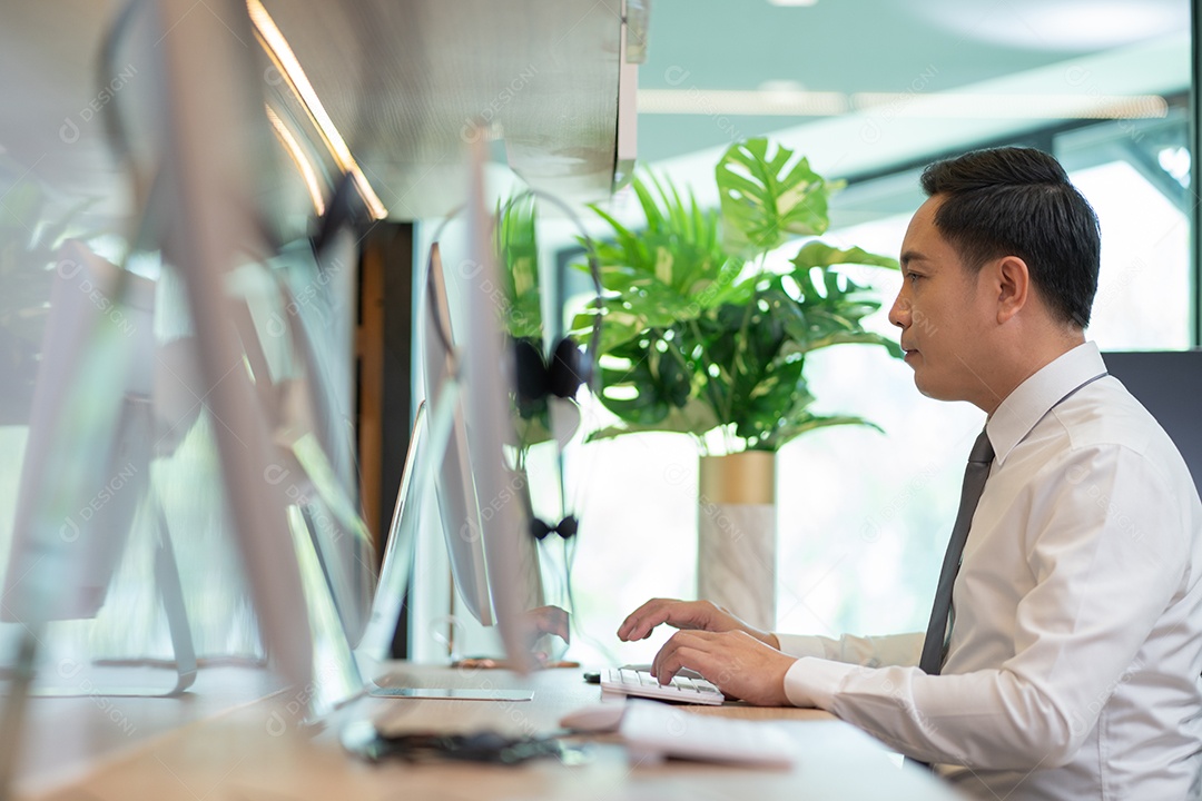 Agente de telemarketing masculino asiático trabalhando no computador na mesa