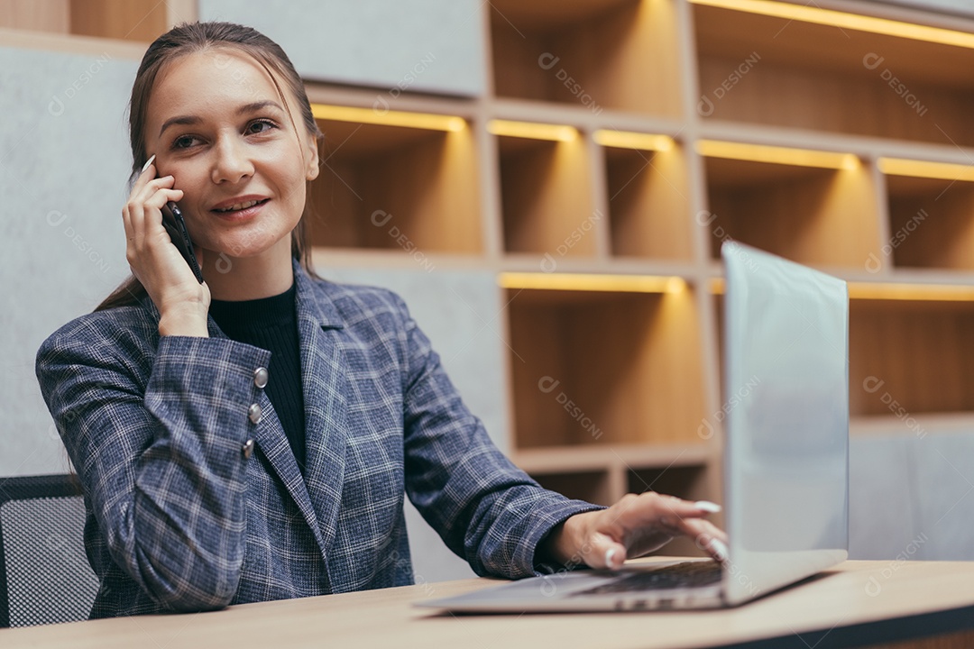 Secretária falando ao telefone na mesa do escritório