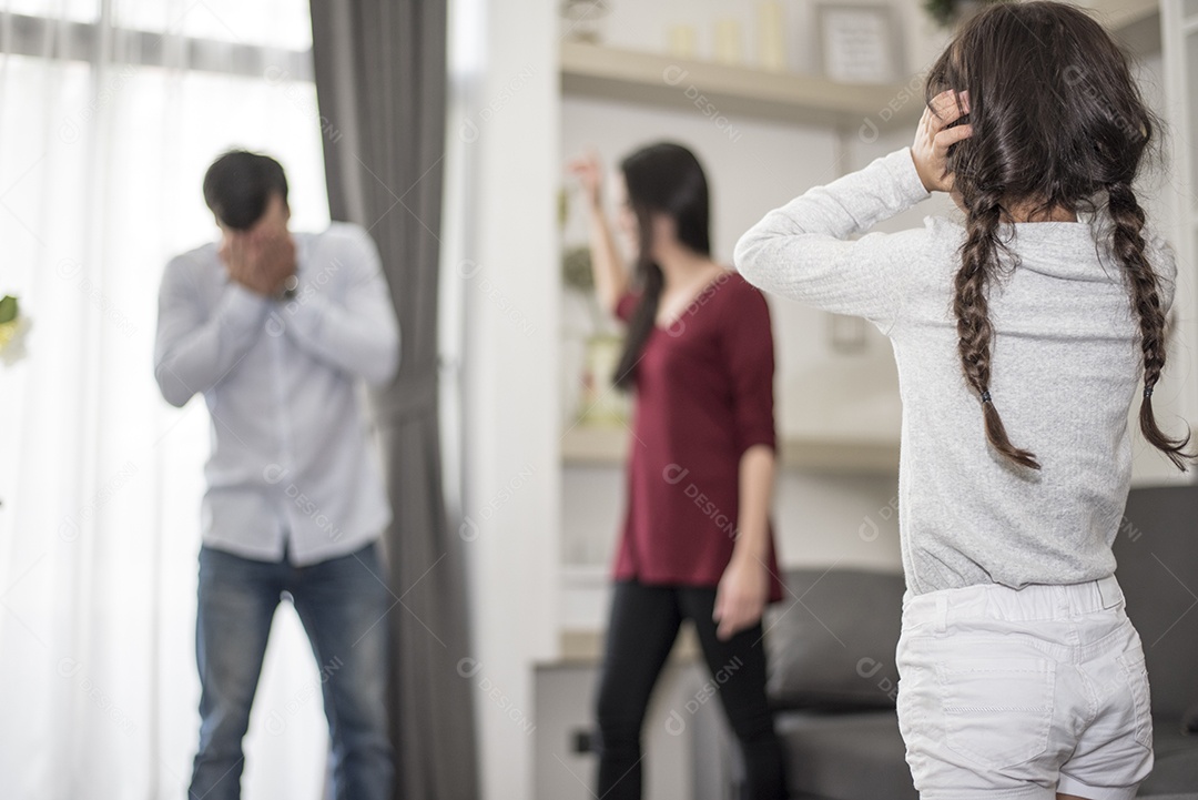 Na visão de trás, a garotinha coloca as mãos nos ouvidos porque não quer ouvir a briga do pai e da mãe. ouvidos fechados, cena dramática familiar, questões de pais, conceito de problema social e de pais.