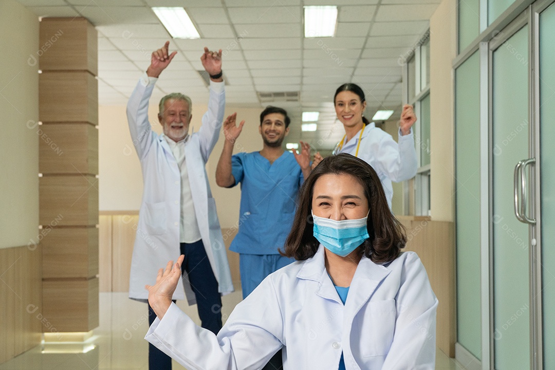 Grupo de equipe médica empurrando cadeira para médica para se divertir depois do trabalho no corredor do hospital.