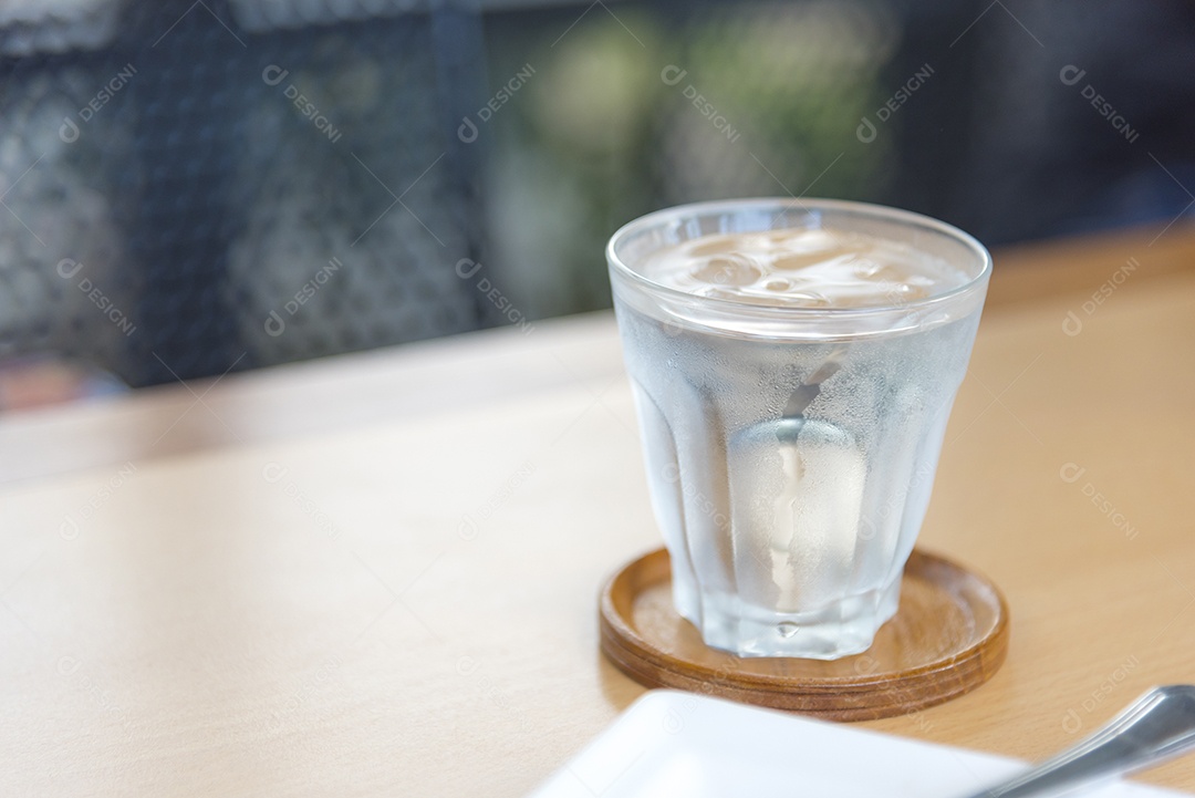 Água mineral em vidro na mesa de madeira com fundo abstrato, foco seletivo no fluxo, bebidas alimentares e conceito de saúde.