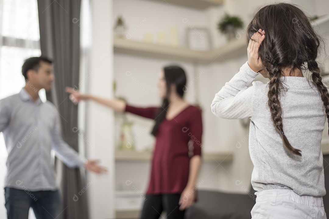 Na visão de trás, a garotinha coloca as mãos nos ouvidos porque não quer ouvir a briga do pai e da mãe. ouvidos fechados, cena dramática familiar, questões de pais, conceito de problema social e de pais.