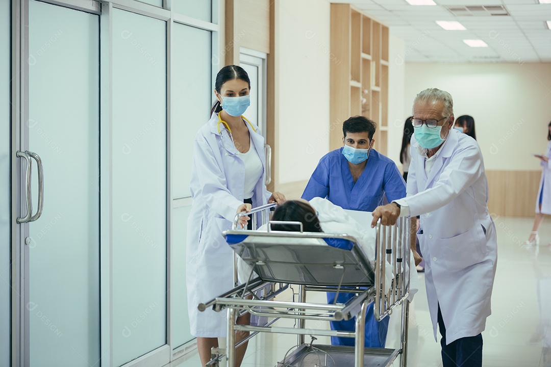 Médico, enfermeira e paramédicos carregando paciente na maca empurrando e correndo em direção à sala de cirurgia do hospital.