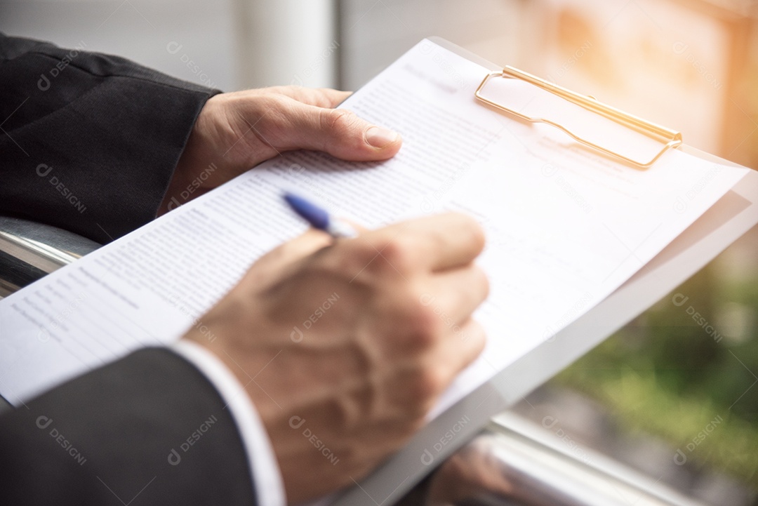 Empresário está assinando no papel de assinatura, conceito de acordo comercial, foco seletivo na mão esquerda.