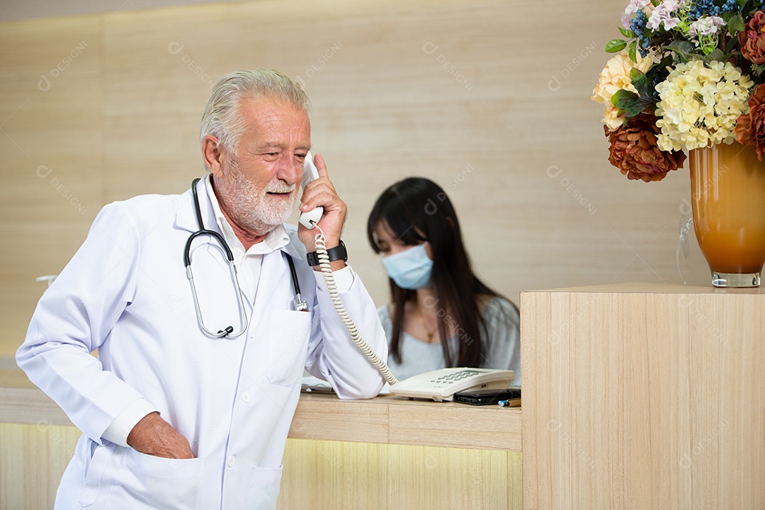 Médico masculino sênior falando ao telefone na recepção