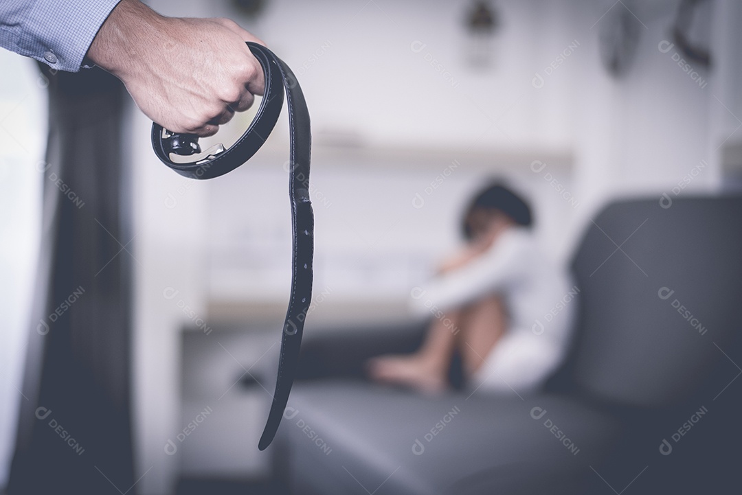 Foco seletivo do cinto na mão do homem estressado contra o borrão abstrato de uma garotinha temendo no momento dramático.